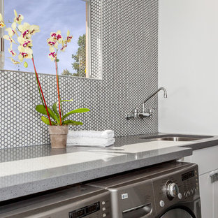 Design ideas for a medium sized midcentury utility room in Orange County with a single-bowl sink, flat-panel cabinets, white cabinets, engineered stone countertops, white walls, ceramic flooring and a side by side washer and dryer.