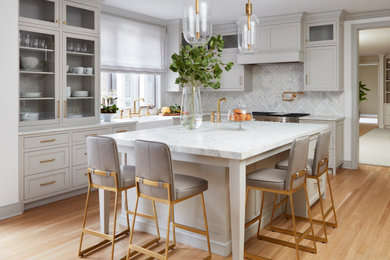 Eat-in kitchen - large traditional u-shaped light wood floor and brown floor eat-in kitchen idea in New York with a farmhouse sink, recessed-panel cabinets, gray cabinets, marble countertops, white backsplash, marble backsplash, paneled appliances, an island and white countertops