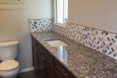 Example of a large transitional master beige tile and glass sheet ceramic tile and brown floor bathroom design in Seattle with recessed-panel cabinets, dark wood cabinets, a two-piece toilet, beige walls and granite countertops