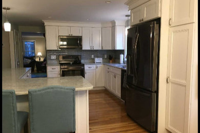 Eat-in kitchen - mid-sized transitional l-shaped light wood floor eat-in kitchen idea in Boston with an undermount sink, recessed-panel cabinets, white cabinets, quartz countertops, gray backsplash, glass tile backsplash, stainless steel appliances, an island and gray countertops