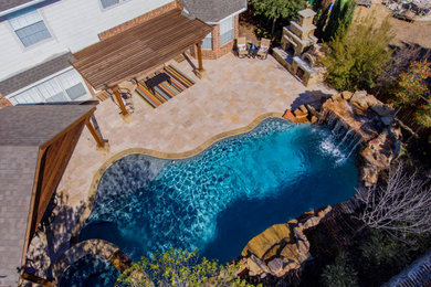 Mid-sized backyard stone and custom-shaped hot tub photo in Dallas