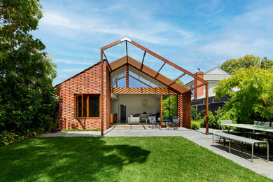 Medium sized and red retro bungalow brick detached house in Melbourne with a pitched roof and a tiled roof.