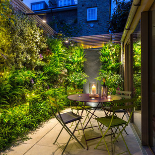 Kleiner Moderner Patio hinter dem Haus mit Pflanzwand und Natursteinplatten in London