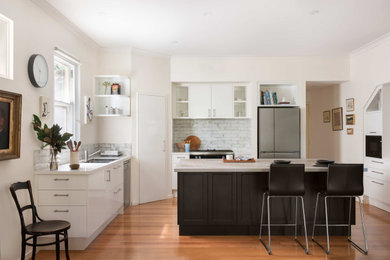 Design ideas for a medium sized contemporary l-shaped kitchen/diner in Perth with a double-bowl sink, white cabinets, engineered stone countertops, white splashback, glass sheet splashback, stainless steel appliances, medium hardwood flooring, an island and white worktops.