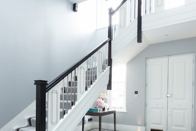 Photo of a traditional painted wood l-shaped staircase in London with painted wood risers.
