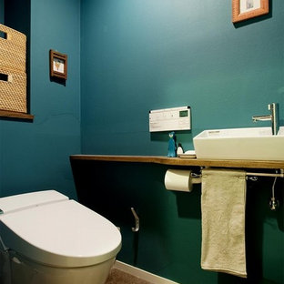 東京23区のエクレクティックスタイルのおしゃれなトイレ・洗面所 (青い壁、ベッセル式洗面器、木製洗面台、茶色い床、ブラウンの洗面カウンター) の写真