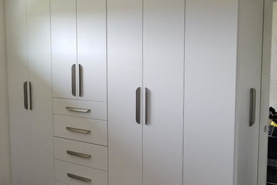 Inspiration for a large timeless gender-neutral dark wood floor and brown floor reach-in closet remodel in Seattle with flat-panel cabinets and white cabinets