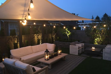 Design ideas for a mid-sized contemporary backyard patio in Vancouver with a fire feature, decking and an awning.
