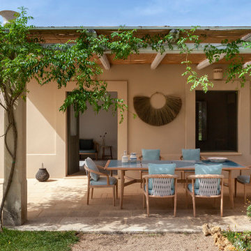 Ein Esszimmer in mediterranen Tönen lädt zum Verweilen unter der Pergola ein