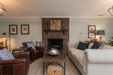Large transitional open concept medium tone wood floor living room photo in Charlotte with blue walls, a standard fireplace, a brick fireplace and no tv