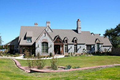 Large elegant gray two-story stone exterior home photo in Austin