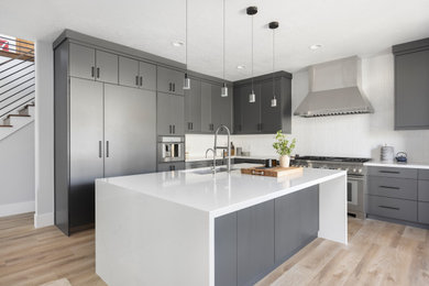 Example of a large minimalist l-shaped laminate floor and brown floor eat-in kitchen design in Salt Lake City with an undermount sink, flat-panel cabinets, blue cabinets, quartz countertops, white backsplash, porcelain backsplash, paneled appliances, an island and white countertops