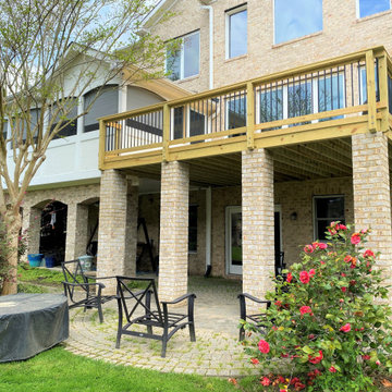 Elevated deck covering a paver patio and connecting to a screened-in porch