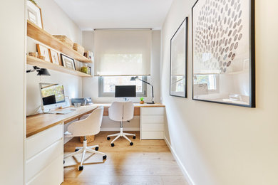 Modelo de despacho nórdico de tamaño medio con paredes beige, suelo de madera clara y escritorio empotrado