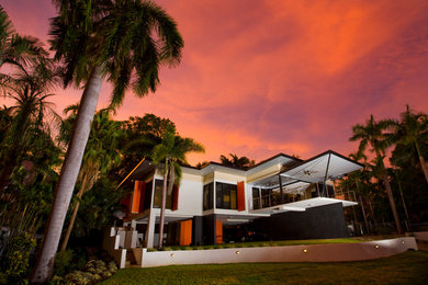 This is an example of a mid-sized tropical two-storey white exterior in Darwin with mixed siding and a flat roof.
