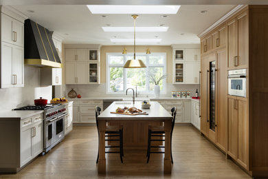Mid-sized trendy u-shaped light wood floor and brown floor enclosed kitchen photo in San Francisco with an undermount sink, shaker cabinets, white cabinets, quartz countertops, white backsplash, granite backsplash, stainless steel appliances, an island and white countertops