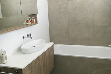 Photo of a mid-sized modern master bathroom in Sydney with light wood cabinets, a drop-in tub, a corner shower, beige tile, ceramic tile, white walls, ceramic floors, a vessel sink and engineered quartz benchtops.