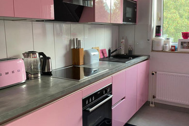 Diseño de cocina lineal actual cerrada sin isla con puertas de armarios rosa y electrodomésticos negros