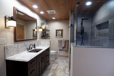Mid-sized arts and crafts master gray tile and ceramic tile single-sink bathroom photo in Grand Rapids with recessed-panel cabinets, brown cabinets, an undermount sink, quartz countertops, a hinged shower door, white countertops and a built-in vanity