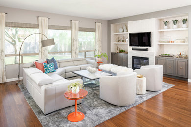 Inspiration for a large mid-century modern open concept medium tone wood floor, brown floor and wallpaper living room remodel in Phoenix with a bar, gray walls, a standard fireplace, a stone fireplace and a wall-mounted tv