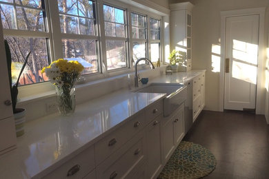 Enclosed kitchen - large cottage u-shaped concrete floor and brown floor enclosed kitchen idea in Other with a farmhouse sink, shaker cabinets, white cabinets, quartz countertops, stainless steel appliances, an island and white countertops