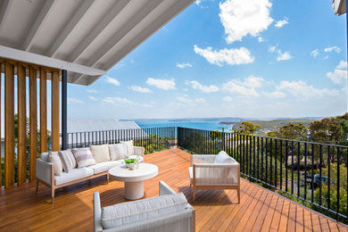 Photo of a mid-sized beach style deck in Sydney with with dock and a roof extension.