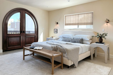 ロサンゼルスにある広いビーチスタイルのおしゃれな主寝室 (ベージュの壁、磁器タイルの床、ベージュの床)