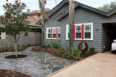 Design ideas for a mid-sized midcentury front yard partial sun garden in Melbourne with a garden path and natural stone pavers.