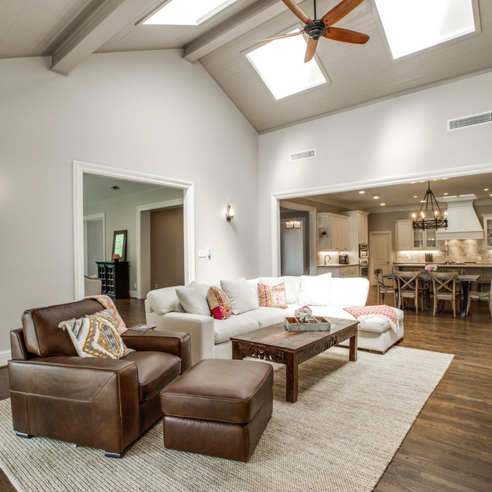 North Dallas Transitional open floor Living Room remodel with cathedral ceiling, multiple large skylights, stone fireplace and dark hardwood flooring. Photo: Realtor