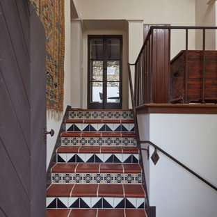 Foto de escalera mediterránea con contrahuellas con baldosas y/o azulejos, escalones de terracota y barandilla de metal