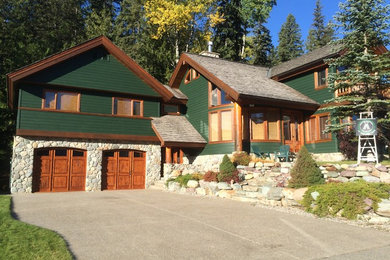 Example of a mid-sized mountain style green two-story wood gable roof design in Calgary