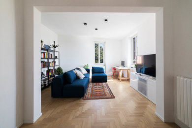 Esempio di un soggiorno moderno di medie dimensioni e aperto con libreria, pareti bianche, parquet chiaro e pavimento marrone
