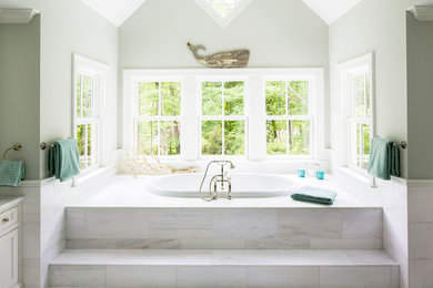 Photo of a large beach style master bathroom in New York with a drop-in tub, recessed-panel cabinets, white cabinets, white tile, stone tile, green walls, marble floors, an undermount sink and marble benchtops.