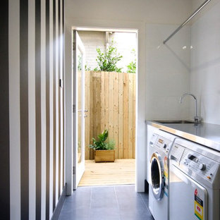 Small contemporary single-wall separated utility room in Sydney with flat-panel cabinets, white cabinets, stainless steel worktops, white walls, ceramic flooring and a side by side washer and dryer.