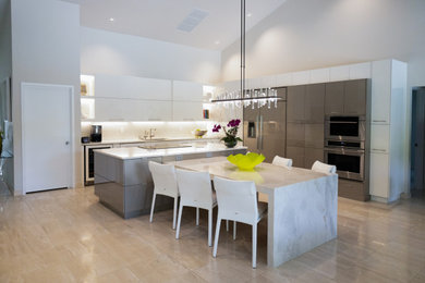 Example of a large trendy l-shaped kitchen design in Miami with flat-panel cabinets, white cabinets, quartzite countertops, white backsplash, glass tile backsplash, paneled appliances and an island