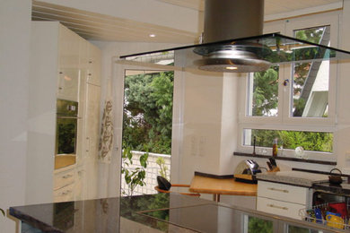 Moderne Küche mit weißen Schränken, Granit-Arbeitsplatte, Keramikboden, Halbinsel und weißem Boden in Sonstige