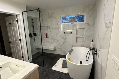 This is an example of a large contemporary ensuite bathroom in Los Angeles with flat-panel cabinets, brown cabinets, quartz worktops, double sinks, a floating vanity unit, a freestanding bath, a built-in shower, a one-piece toilet, white tiles, marble tiles, white walls, marble flooring, a submerged sink, black floors, an open shower, white worktops and a shower bench.