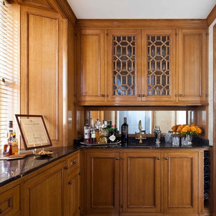 ニューヨークのトラディショナルスタイルのおしゃれなウェットバー (アンダーカウンターシンク、家具調キャビネット、中間色木目調キャビネット、無垢フローリング、ミラータイルのキッチンパネル) の写真