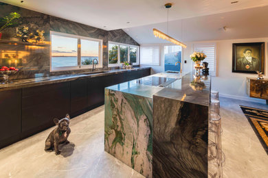 Inspiration for a large contemporary ceramic tile and gray floor kitchen remodel in Auckland with a double-bowl sink, flat-panel cabinets, black cabinets, quartzite countertops, multicolored backsplash, stone slab backsplash, black appliances, an island and multicolored countertops