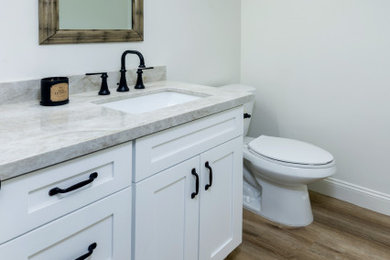 Bathroom - mid-sized transitional gray tile vinyl floor, brown floor and single-sink bathroom idea in San Diego with shaker cabinets, white cabinets, a two-piece toilet, an undermount sink, quartzite countertops, gray countertops and a freestanding vanity