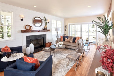 Inspiration for a mid-sized country formal and enclosed medium tone wood floor and brown floor living room remodel in Other with white walls, a standard fireplace, a stone fireplace and no tv