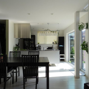 Inspiration pour une salle à manger ouverte sur le salon minimaliste avec un mur blanc, un sol en contreplaqué et un sol gris.