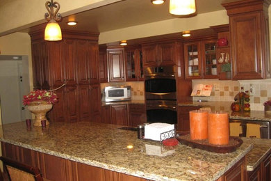 Open concept kitchen - mid-sized traditional l-shaped open concept kitchen idea in Chicago with raised-panel cabinets, medium tone wood cabinets, granite countertops, beige backsplash, stainless steel appliances and an island