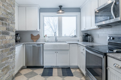 Photo of a small country u-shaped kitchen pantry in Minneapolis with a farmhouse sink, beaded inset cabinets, white cabinets, granite benchtops, white splashback, ceramic splashback, stainless steel appliances, no island and linoleum floors.