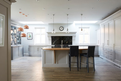 Design ideas for a traditional kitchen/diner in London with shaker cabinets, white cabinets and dark hardwood flooring.