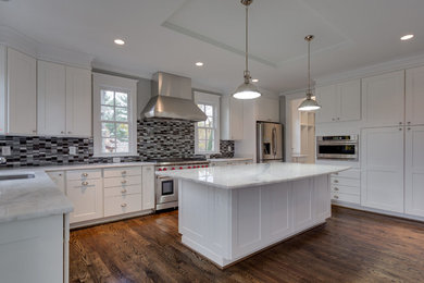 Large transitional u-shaped separate kitchen in DC Metro with an undermount sink, shaker cabinets, white cabinets, quartzite benchtops, grey splashback, glass tile splashback, stainless steel appliances, dark hardwood floors, with island, brown floor and white benchtop.