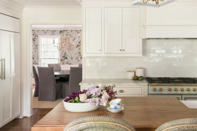 Example of a kitchen design in Charlotte with white cabinets and an island