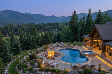 Inspiration for a mid-sized rustic backyard stone and custom-shaped hot tub remodel in Columbus