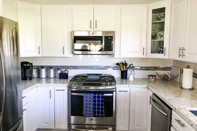 Example of a mid-sized transitional u-shaped medium tone wood floor and brown floor open concept kitchen design in Orange County with an undermount sink, raised-panel cabinets, white cabinets, quartzite countertops, white backsplash, porcelain backsplash, stainless steel appliances, a peninsula and white countertops