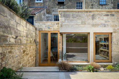 Ejemplo de fachada de piso beige actual de tamaño medio de una planta con revestimiento de piedra, tejado plano y techo verde